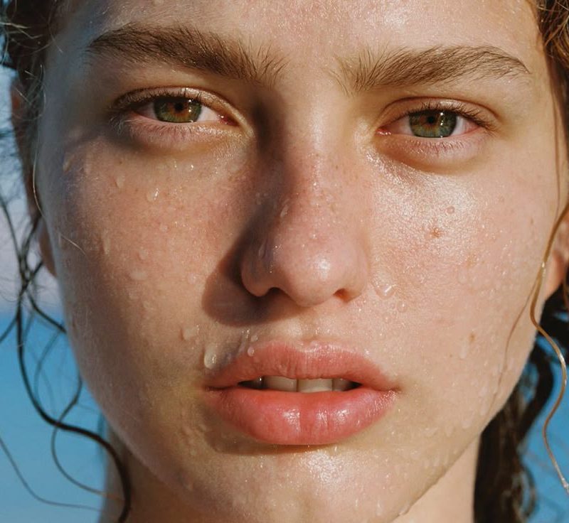 Woman with radiant skin enjoying summer outdoors, highlighting healthy glowing complexion