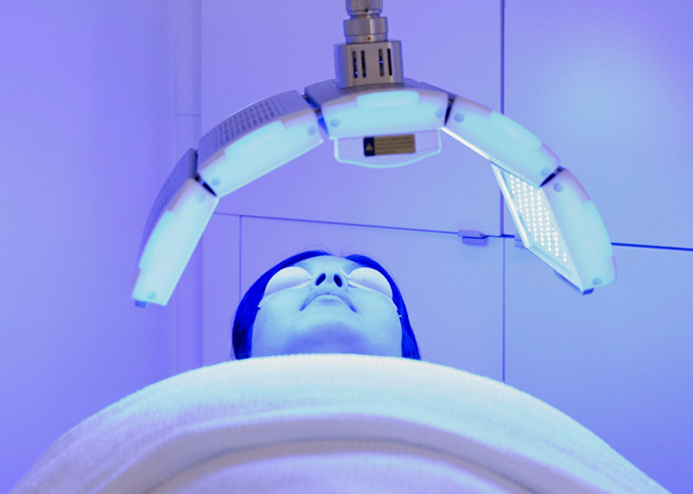 Patient receiving blue LED light therapy in clinic.