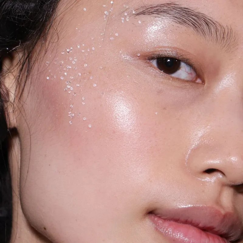 Close-up of a woman with radiant, deeply hydrated, and dewy skin featuring subtle frost or crystal details on her face.