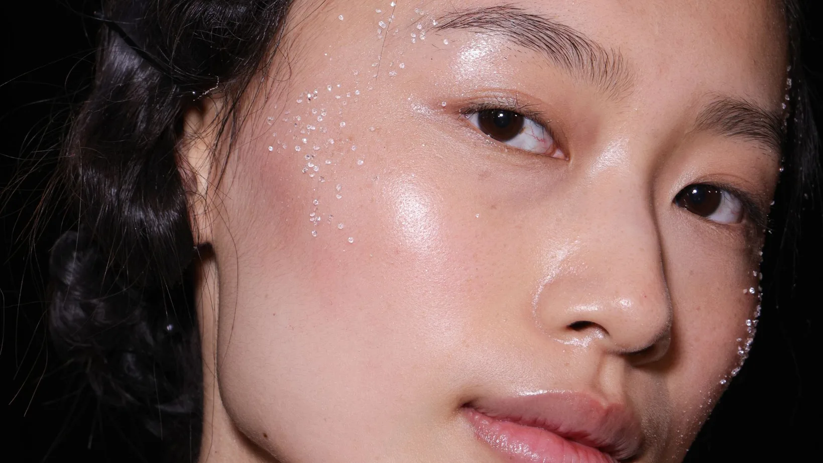 Close-up of a woman with radiant, deeply hydrated, and dewy skin featuring subtle frost or crystal details on her face.