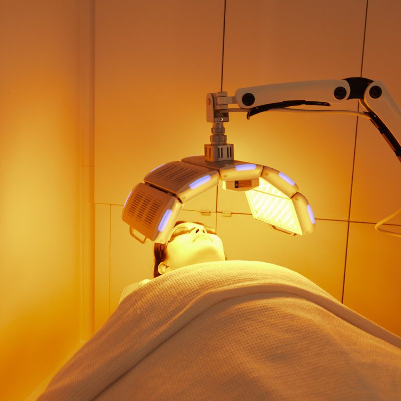 Client receiving a soothing yellow LED light therapy facial treatment to calm redness and support skin tone at Body Sculpting Clinics Sydney.