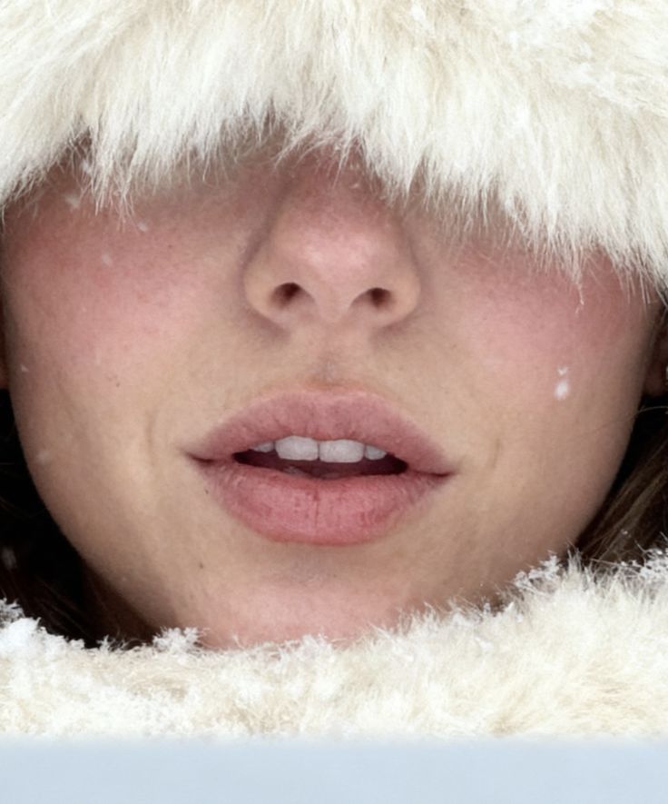 Close-up of a person's rosy winter complexion framed by white fur, highlighting skin renewal during cold, low-UV months.